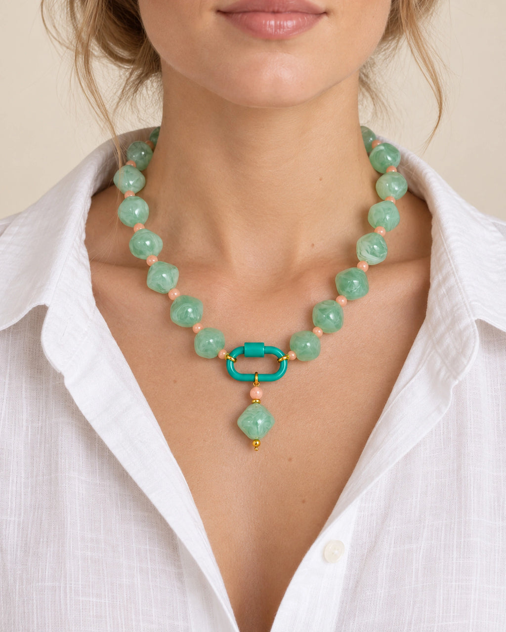 Mint green with peach accents acrylic beaded necklace with a mint-green rounded diamond pendant, worn at the neckline.