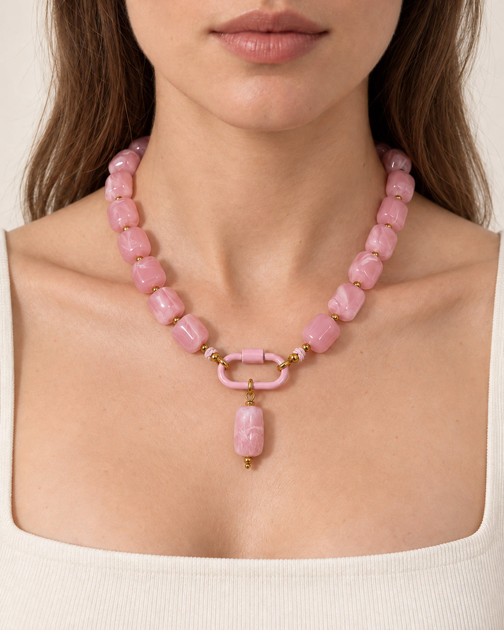 Pink acrylic beaded necklace with a pink oval pendant, worn at the neckline.