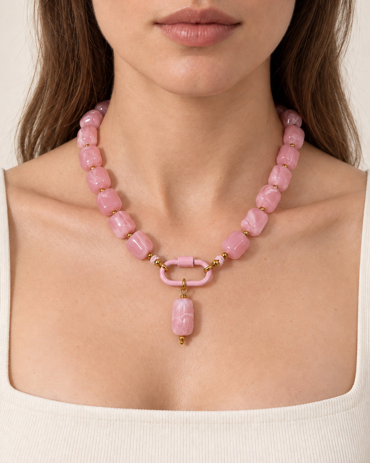 Pink acrylic beaded necklace with a pink oval pendant, worn at the neckline.