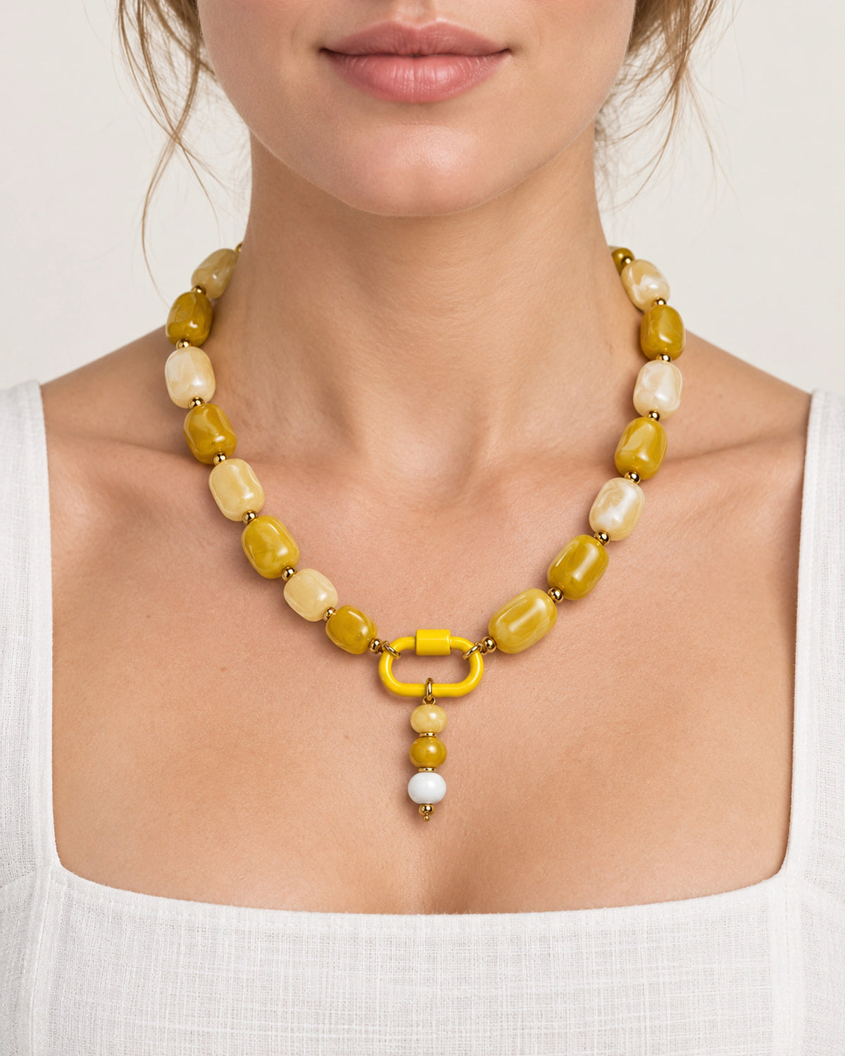 Yellow and cream acrylic beaded necklace with a yellow and white beaded drop pendant, worn at the neckline.