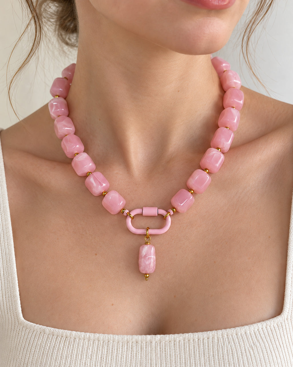 Pink acrylic beaded necklace with a pink oval pendant, shown in a close-up styling view.