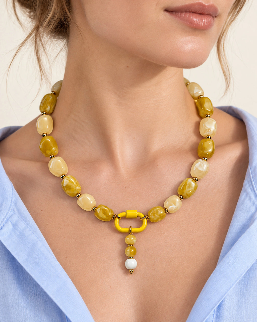 Yellow and cream acrylic beaded necklace with a yellow and white beaded drop pendant, shown in a close-up styling view.