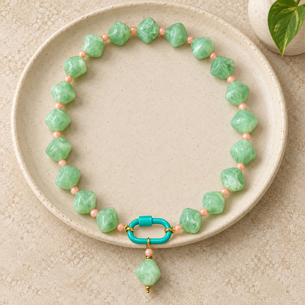 Mint green with peach accents acrylic beaded necklace with a mint-green rounded diamond pendant arranged in a styled still-life setting.
